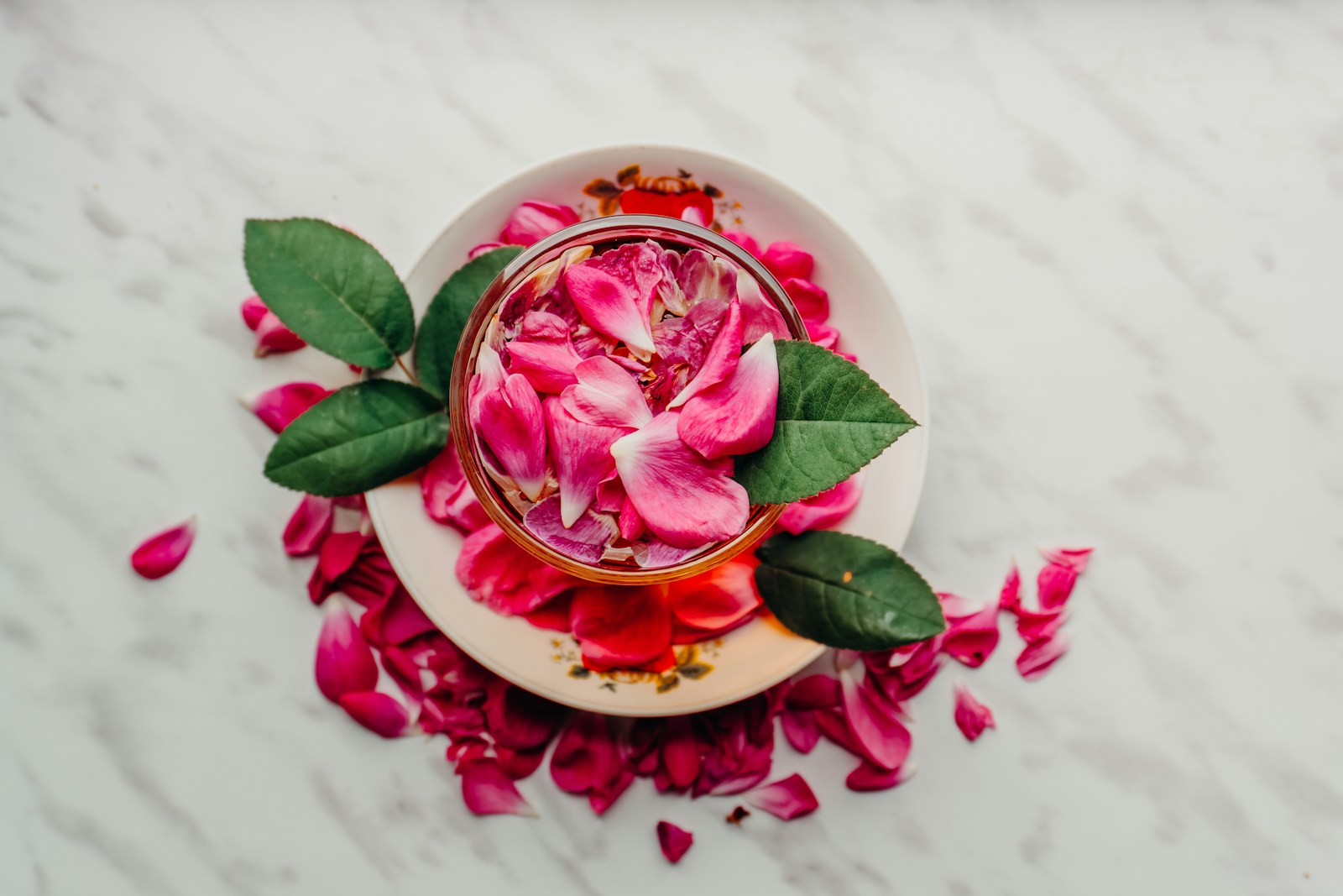 Pink rose petals in a bowl with leaves